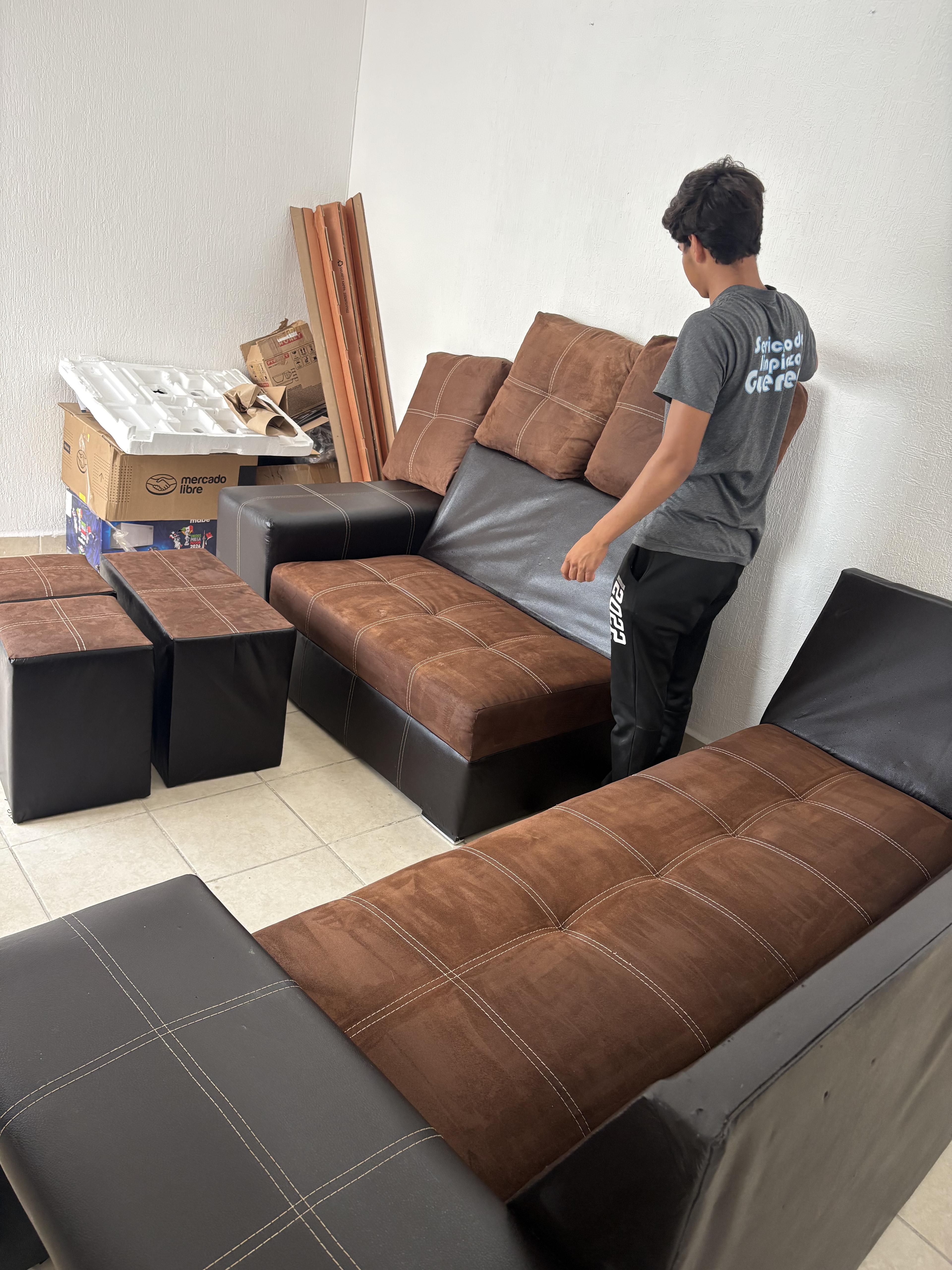 Persona organizando un juego de sala marrón en una habitación con cajas.